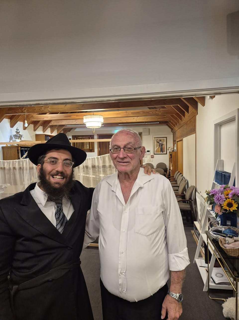 A rabbi and a congregant standing together in the sanctuary at 788