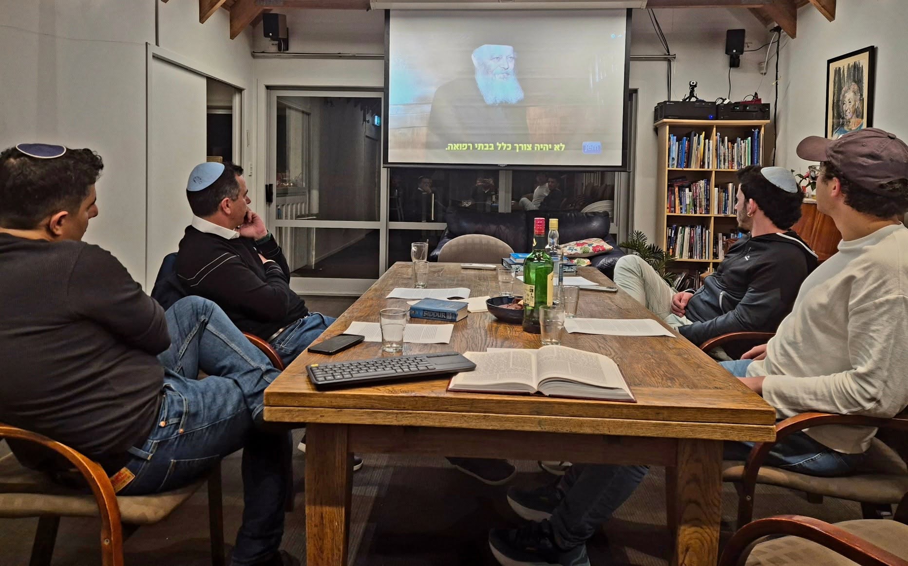 Men seated around a long table at 788 watching a projected class